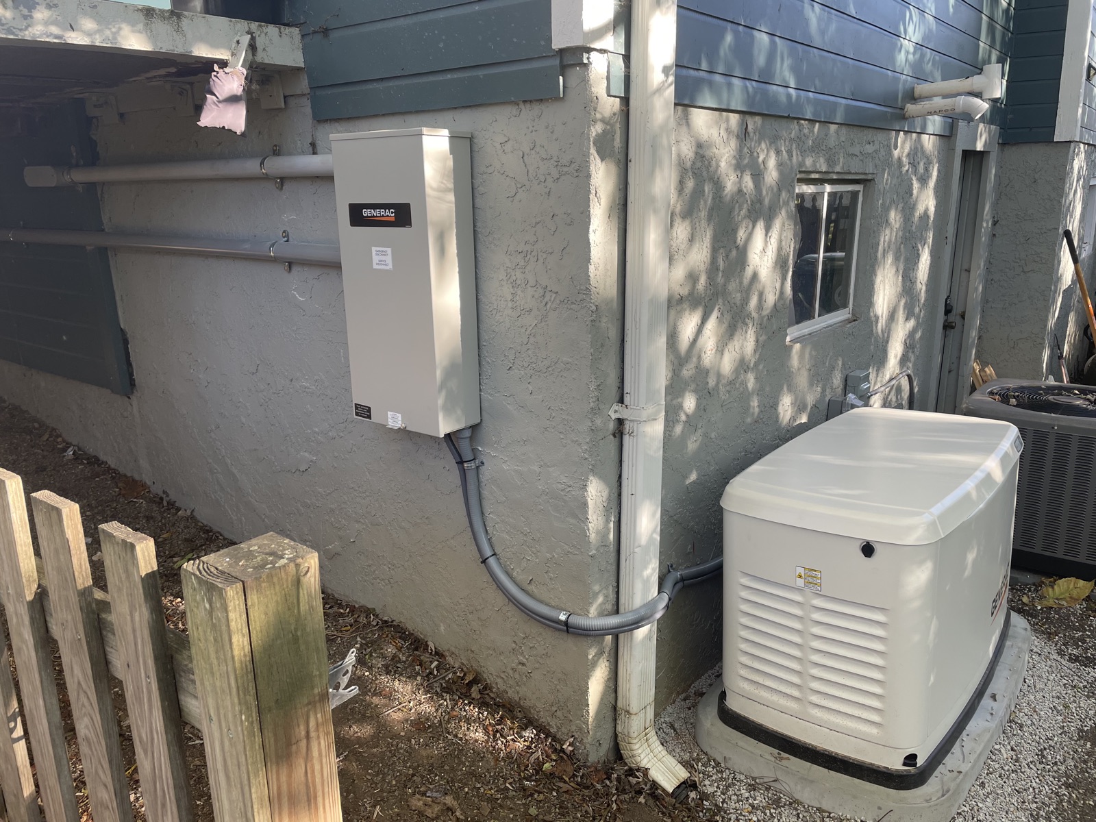 A Generac standby generator and transfer panel installed by Power to the People on the side of a residential home